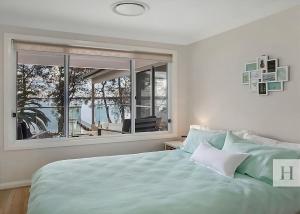 a bedroom with a large bed and a large window at Enjoy Lazy Daze in Summerland Point