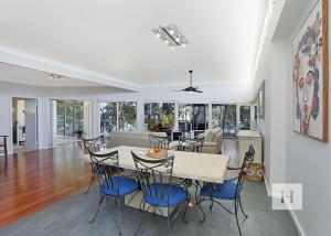 a dining room and living room with a table and chairs at Karinyah in Summerland Point