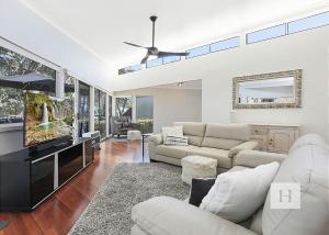 a living room with white furniture and a flat screen tv at Karinyah in Summerland Point