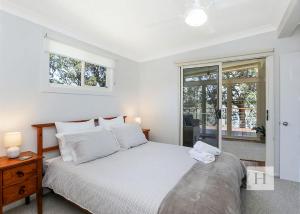 a white bedroom with a bed and a window at Karinyah in Summerland Point