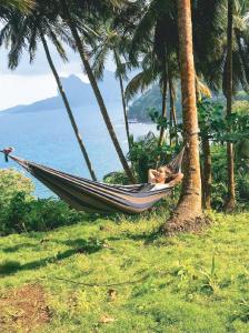 a woman laying in a hammock in front of the ocean at Roça Atalaia in Nova Estrela