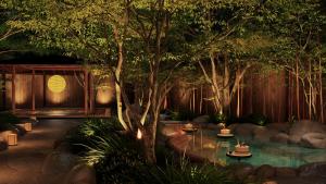 a garden with a pond with trees and lights at Gensen Itto Minamiizu in Minamiizu