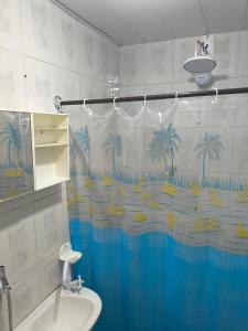 a bathroom with a sink and a shower curtain with palm trees at Microcasa Caledônia Nova Friburgo in Nova Friburgo