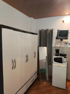a kitchen with white cabinets and a tv and a microwave at Microcasa Caledônia Nova Friburgo in Nova Friburgo