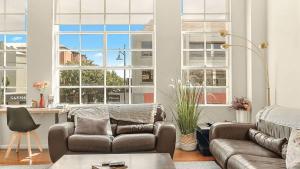 a living room with a couch and a table and windows at New York Style Apartment in Bendigo +10 photos