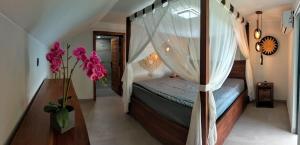 a bedroom with a canopy bed with a vase of flowers at Villa Claudine in Ambengan