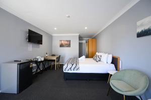 a hotel room with a bed and a desk and a kitchen at Old Maitland Inn - Rutherford in Maitland