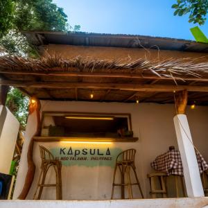 a restaurant with stools in front of a building at Kapsula El Nido in El Nido
