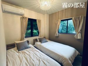 two beds in a room with two windows at HARMONIA 那須 Nas-MAX26名-川遊び-BBQ-カラオケのできる宿 in Nasu