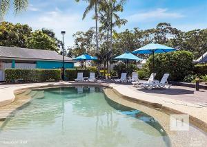 a swimming pool with chairs and umbrellas at Lakeshores Villa in Cams Wharf