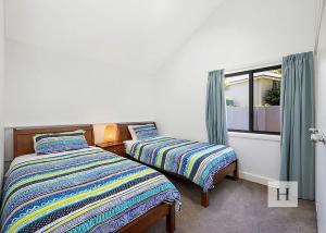 two beds in a room with a window at Lakeshores Villa in Cams Wharf
