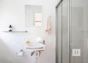a white bathroom with a sink and a shower at Lakeshores Villa in Cams Wharf +9 photos