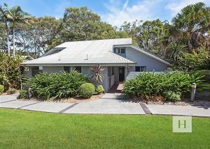 a white house with a landscaped yard at Lakeshores Villa in Cams Wharf