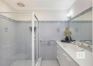 a white bathroom with a shower and a sink at Mannering Lake House in Mannering Park +17 photos