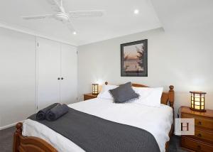a bedroom with a bed with white sheets and a ceiling at Mannering Lake House in Mannering Park