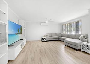 a living room with a couch and a flat screen tv at The Sailor s Haven in Mannering Park