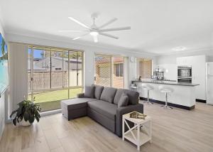 a living room with a couch and a kitchen at The Sailor s Haven in Mannering Park