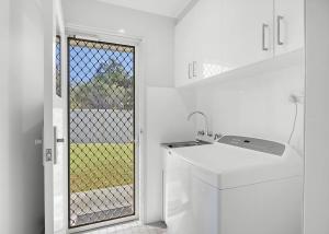 a white kitchen with a sink and a window at The Sailor s Haven in Mannering Park +10 photos