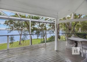 a dining room with a table and chairs on a deck at Relaxing Getaway in Summerland Point