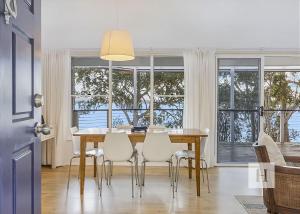 a dining room with a table and chairs and windows at Relaxing Getaway in Summerland Point