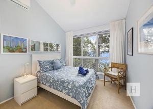 a bedroom with a bed and a chair and windows at Relaxing Getaway in Summerland Point