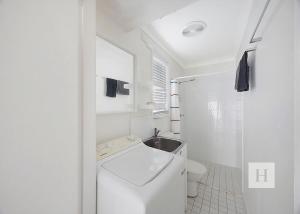 a white bathroom with a toilet and a sink at Relaxing Getaway in Summerland Point +14 photos