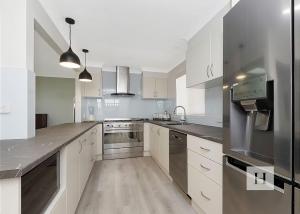 a large kitchen with white cabinets and stainless steel appliances at Paradise Palms in Mannering Park
