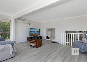 a living room with a couch and a tv at Paradise Palms in Mannering Park