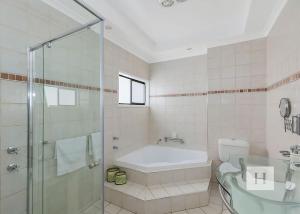 a bathroom with a tub and a shower and a sink at Paradise Palms in Mannering Park +13 photos