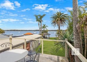 a balcony with a view of the water and palm trees at Paradise Palms in Mannering Park