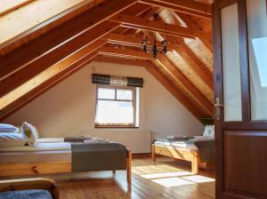 a attic room with two beds and a window at Panoráma Villa Vágáshuta in Vágáshuta