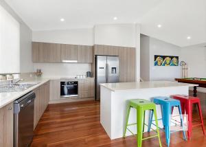 a kitchen with three colorful stools in front of a counter at Sunset Central Coast in Mannering Park +15 photos