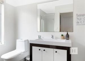a white bathroom with a sink and a mirror at Sunset Central Coast in Mannering Park