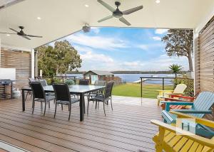 a dining room with a table and chairs on a deck at Sunset Central Coast in Mannering Park