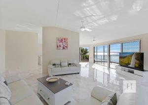 a white living room with a couch and a tv at Sunset Lakehouse in Toukley