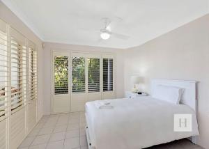 a white bedroom with a white bed and a window at Sunset Lakehouse in Toukley