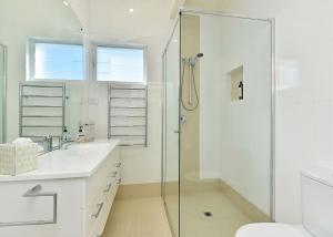 a white bathroom with a shower and a sink at The Sea Serenade in Blacksmiths +30 photos