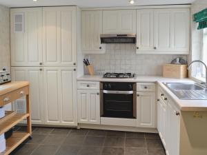 a kitchen with white cabinets and a stove top oven at Swiss Cottage in Chideock