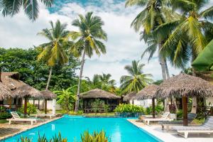 a pool at a resort with palm trees at Bungalow du Lagon in Ambaro