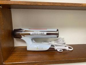a hair dryer sitting on a wooden shelf with a pile of books at お宿るり嘉鉄 in Setouchi