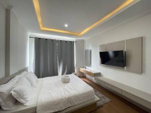 a bedroom with a white bed and a flat screen tv at Sanur House Lavender in Sanur +29 photos