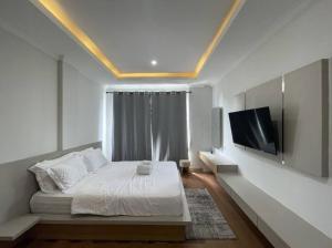 a bedroom with a bed and a flat screen tv at Sanur House Lavender in Sanur