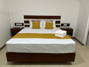 a bedroom with a large bed with yellow and white pillows at Hillkandy in Kengalla