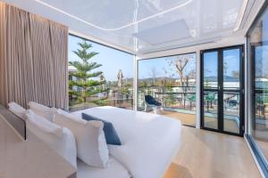 a living room with white furniture and large windows at Air Space Camp Khao Yai in Pak Chong