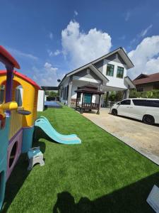 a playground with a train and a slide in front of a house at Infra Homestay 1 in Marang