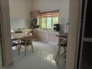 a kitchen with a table and chairs and a table and a counter at Infra Homestay 1 in Marang