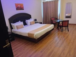 a hotel room with a bed and a table and chairs at Hotel Gentleman Mithila in Eramalloor