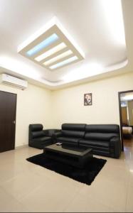 a living room with black leather furniture and a skylight at Hotel Gentleman Mithila in Eramalloor