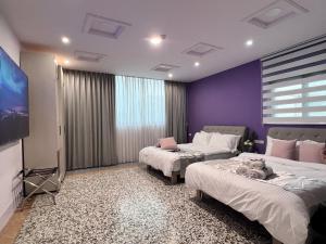 a room with two beds and a flat screen tv at Aren Inn in Zhushan