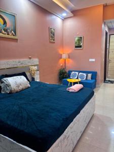 a bedroom with a large bed and a blue couch at Good vibes only gaur city center studio apartment in Ghaziabad +10 photos